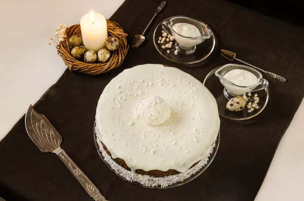 Easter cake with cream  icing and burning candle — Stock Photo, Image