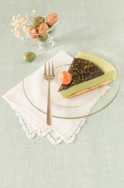 Piece of easter cake with tea matcha decorated chocolate ganache and sweet-stuff eggs on glass plate — Stock Photo, Image