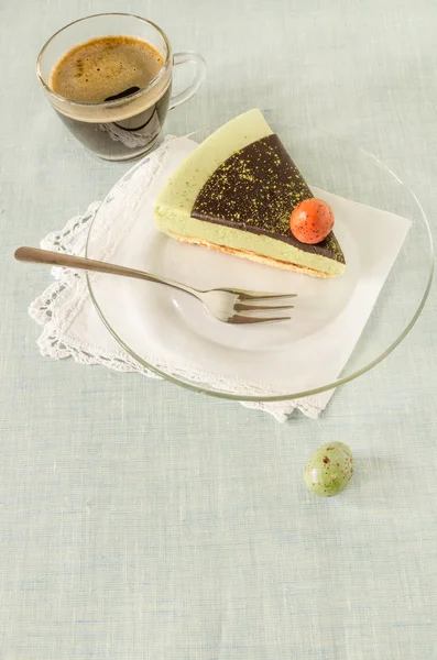 Кусок пасхального торта с чаепитием, украшенным шоколадным ганаче и яичницей из сладкого на стеклянной тарелке — стоковое фото