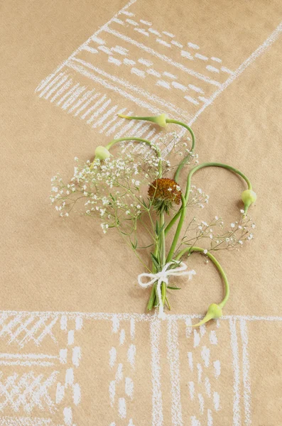 Νεκρή φύση με σκόρδο μπουμπούκια και μπουκέτο λουλούδια στη σκιτσογραφία χαρτί με πετσέτα — Φωτογραφία Αρχείου