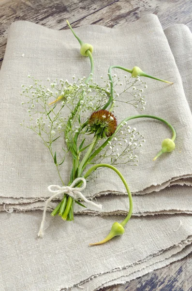 にんにくの芽とリネンのテーブル クロスの上に花束花のある静物 — ストック写真