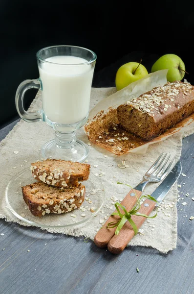 Zelfgebakken brood met appels in inpakpapier en glas melk op wit bord — Stockfoto