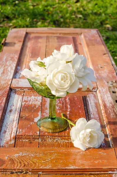 Schöner Rosenstrauß mit Tropfen in grüner Glasvase auf altem Holztisch — Stockfoto