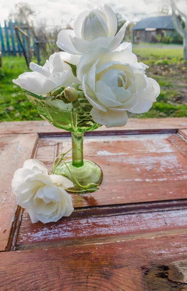 Schöner Rosenstrauß mit Tropfen in grüner Glasvase auf altem Holztisch — Stockfoto