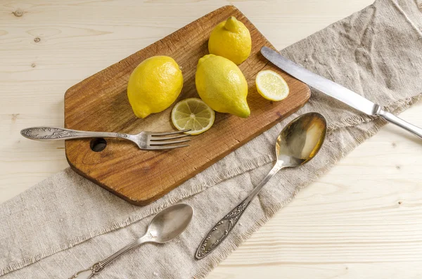 Fruits et tranches de citron sur une vieille planche à découper en bois — Photo