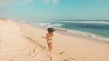 Genç ve çekici bir kadın okyanusun yakınındaki kumsalda dinleniyor.