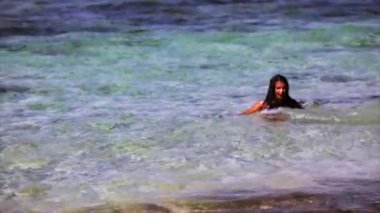 Genç ve çekici bir kadın okyanusun yakınındaki kumsalda koşuyor ve eğleniyor.