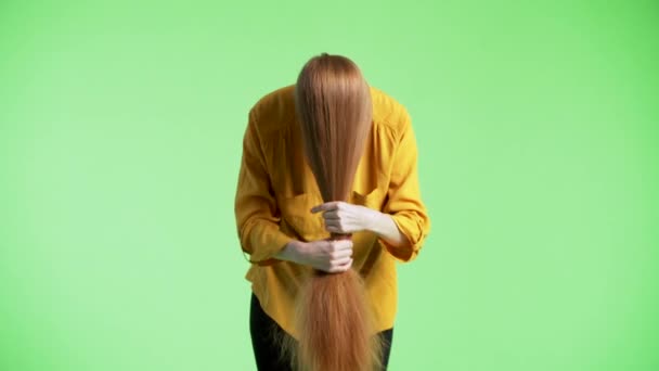 女人的脸上都是姜黄的头发 拿着它们 抚摸着它们 扭伤了它们的手腕 绿色背景 — 图库视频影像