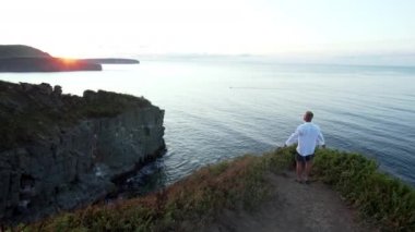 Denizde kayaların üzerinde duran mutlu adam