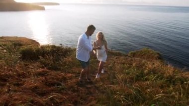 Hamile kadın ve erkek denizde kayalarda yürüyorlar.