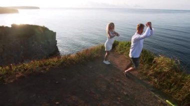 Hamile kadın ve erkek denizin kayalıklarında dikiliyorlar.