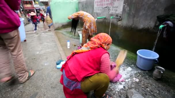 Women wash clothes and soap head at hot strings on the street. — Stock Video