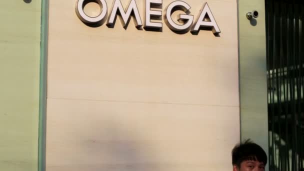 People near Omega logo — Stock Video
