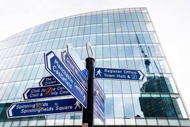 Manchester şehir merkezinde, Şubat 2026 'da mavi yönlü parmak izi. İşaretler, Spinningfields, Manchester Central, Castlefield ve Sivil Adalet Merkezi 'nin de aralarında bulunduğu büyük simgelere işaret ediyor.