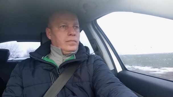 A man rides in the front seat of a car and looks out the window — Stock Video