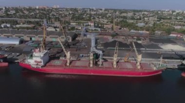 Limana demirlemiş bir kargo gemisi iskele vinçleri tarafından yüklenmeyi bekliyor.
