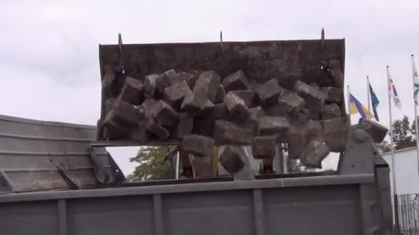 Kazı kovası taştan bir kaldırım taşını bir kamyonun arkasına yüklüyor. — Stok video