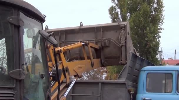 Ведро экскаватора загружает камень в кузов грузовика — стоковое видео