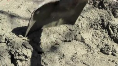 Bir işçi inşaat alanında kürek ve mala kullanarak beton karışımı hazırlar.