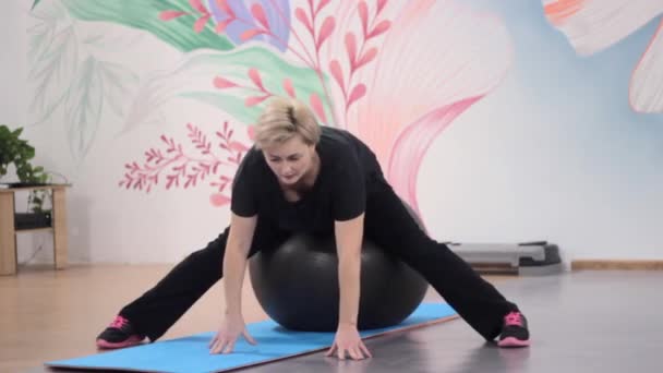 Mädchen in der Turnhalle ist mit Fitness auf einem großen Ball beschäftigt — Stockvideo