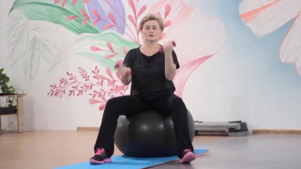 Fitnesstraining mit Kurzhanteln auf dem großen Ball — Stockvideo