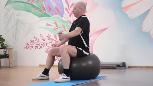 Muž zapojený do fitness skoky na míč a pracuje s činky — Stock video