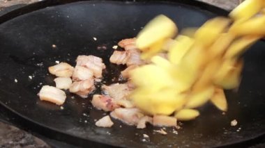 Büyük bir tavada domuz yağı ve etle dilimlenmiş patates spatulasıyla karıştırılıyor. Yüksek kaliteli FullHD görüntüler