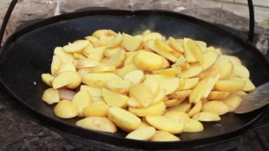 Büyük bir tavada domuz yağı ve etle dilimlenmiş patates spatulasıyla karıştırılıyor. Yüksek kaliteli FullHD görüntüler