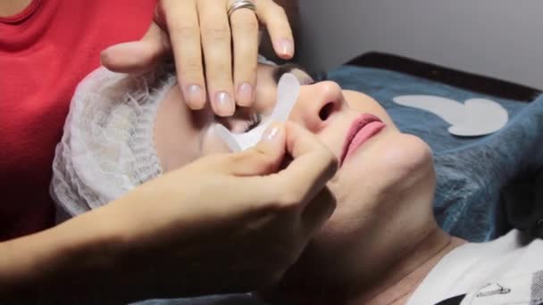 In a beauty salon a woman undergoes an eyelash extension procedure — Stock Video