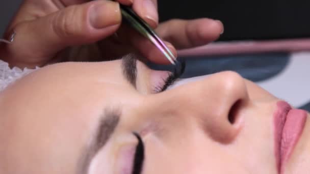 Egy szépségszalonban egy nőt szempilla-hosszabbítási eljárásnak vetnek alá — Stock videók