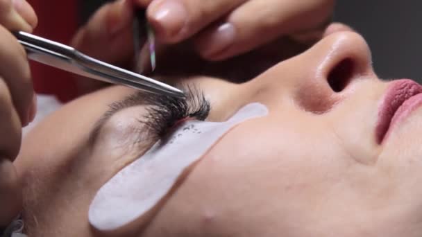Egy szépségszalonban egy nőt szempilla-hosszabbítási eljárásnak vetnek alá — Stock videók