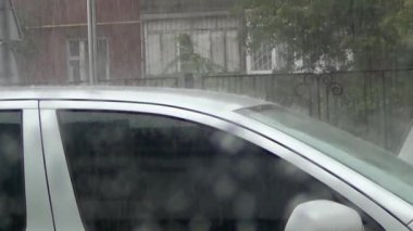 Şiddetli yağmur damlaları ve otoparktaki arabaların çatısı.