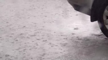 Otoparkta şiddetli yağmur var. Arabanın bir kısmını ve yağmur damlalarını görebilirsiniz.