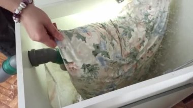 Yastık kılıfındaki işçi, yastık tavuk tüylerinin içeriğini silkeliyor ve temizlik ve dezenfeksiyon için makineye tüy döküyor. İyi uykular.