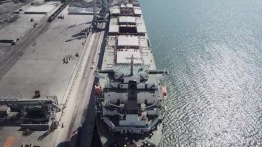 Bir limanda tahıl yükleyen büyük bir geminin üzerinde konveyör makinesiyle kamera uçuşu. Buğday ihracatı. Deniz ihracatı. Tarım. Kuş bakışı. hava görüntüsü