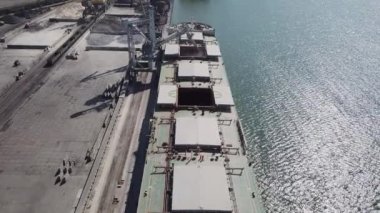 Bir limanda tahıl yükleyen büyük bir geminin üzerinde konveyör makinesiyle kamera uçuşu. Buğday ihracatı. Deniz ihracatı. Tarım. Kuş bakışı. hava görüntüsü