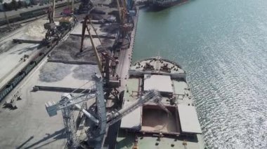 Bir limanda tahıl yükleyen büyük bir geminin üzerinde konveyör makinesiyle kamera uçuşu. Buğday ihracatı. Deniz ihracatı. Tarım. Kuş bakışı. hava görüntüsü