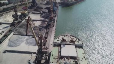 Bir limanda tahıl yükleyen büyük bir geminin üzerinde konveyör makinesiyle kamera uçuşu. Buğday ihracatı. Deniz ihracatı. Tarım. Kuş bakışı. hava görüntüsü