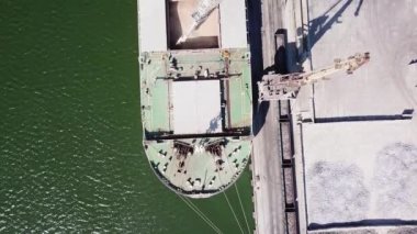 Kameranın büyük bir deniz gemisinin üzerinden geçişi. Kamera aşağıya bakıyor. Gemi limana demirlemiş, tahıl yükleme makinesiyle. Buğday ihracatı. Deniz ihracatı. hava görüntüsü