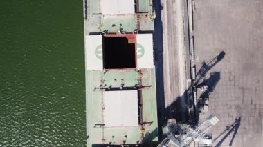 Kameranın büyük bir deniz gemisinin üzerinden geçişi. Kamera aşağıya bakıyor. Gemi limana demirlemiş, tahıl yükleme makinesiyle. Buğday ihracatı. Deniz ihracatı. hava görüntüsü