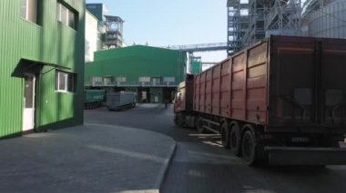 Karavanı olan bir kamyon depo terminaline tahıl boşaltmaya gider. Diğer kamyonlar yükleme tesisinin yakınına park edilmiş. Kamera arkadan seyahat yönünden uçuyor.