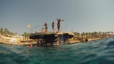 Yazın, tanınmayan insanlar köprüden sıcak denize atlarlar. Dalıştan sonra hava kabarcıkları. GoPro