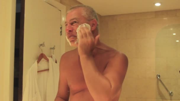 Homme appliquant du gel à raser mousse face à un miroir — Video