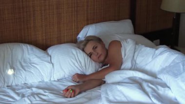 Güzel genç bir kadın rahat bir yatakta uyur yumuşak bir yastıkta beyaz çarşaflı, huzurlu bir uyku, dinlenme, sabahın erken saatlerinde sağlıklı bir uyku.