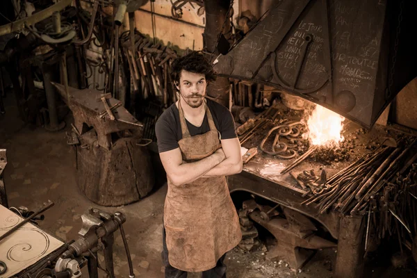 Ironworker forging hot iron in workshop — Stock Photo, Image