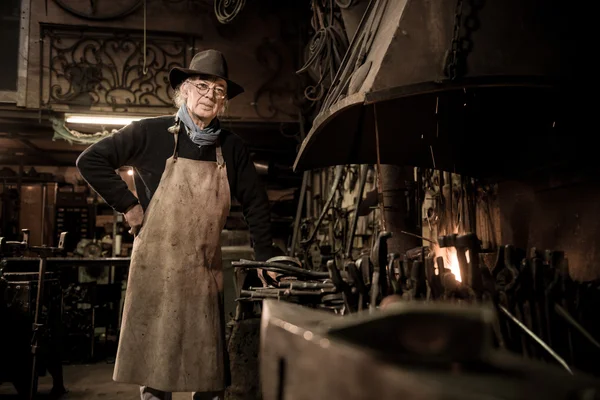 Ironworker forging hot iron in workshop — Stock Photo, Image