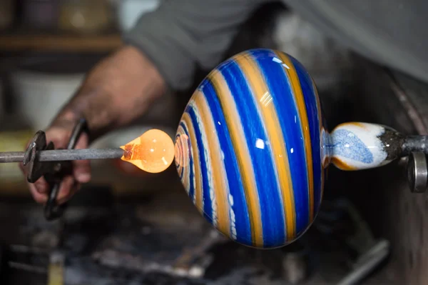 Glassbloover формирует расплавленное стекло в своей мастерской — стоковое фото