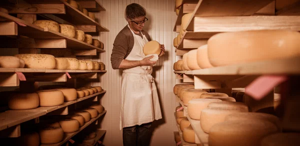 Käsemacher putzt Käse in seiner Werkstatt — Stockfoto