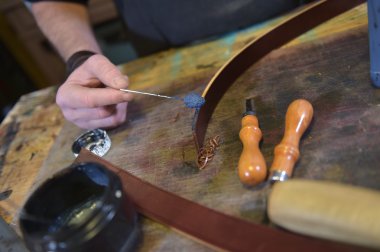 Leather goods craftsman at work in his workshop clipart