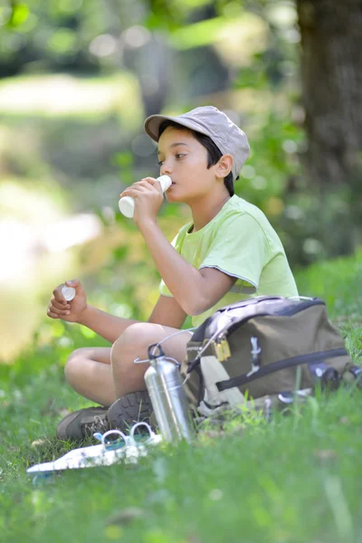 Teyoung jongen zitten in het gras drinken melk te drinken — Stockfoto